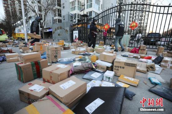 资料图：快递员为居民查找快递物品。<a target='_blank'  data-cke-saved-href='http://www.chinanews.com/' href='http://www.chinanews.com/'>中新社</a>记者 赵隽 摄